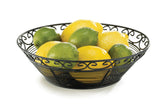 A TableCraft BK27508 black powder coated metal basket with a decorative swirl pattern holds several whole lemons and limes. Part of the Mediterranean Collection Basket line, it displays the vibrant fruit beautifully against a white background.
