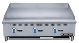 A stainless steel heavy duty gas griddle with three blue control knobs, a smooth flat cooking surface, vent slots above the knobs, sturdy legs, and the BLUELINE logo on the lower right front panel. This 36 inch gas griddle is clean and unused.
