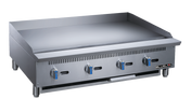 A large stainless steel heavy duty gas griddle with four blue-handled manual control knobs, a flat cooking surface, raised back and sides, vent slits, and short legs. The “BLUEVAN” logo appears on the lower right front panel.