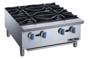 A stainless steel commercial gas stovetop with four burners, heavy cast iron grates, and blue-silver knobs rests on short metal legs. Ideal for countertop use, the clean “BLUELMA” unit stands against a plain background.