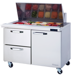 A stainless steel refrigerated prep table on wheels, with an open top displaying assorted sliced vegetables and toppings in bins. The unit features two drawers, a cabinet, and a digital temperature display on the front.