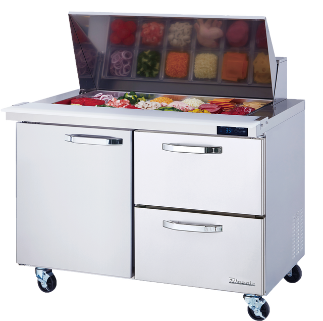 A commercial mega top prep table with a transparent lid open, revealing various chopped vegetables and toppings in containers. Below are two drawers and a cabinet door, all on wheels, with a digital temperature display on the right.