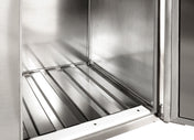 A close-up view of the inside of a stainless steel appliance, possibly featuring a keg floor rack, shows clean, shiny metal surfaces, a grooved bottom panel, and an open door on the right side. The interior appears empty and well-maintained.