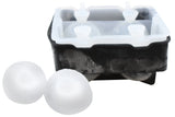 A black silicone ice tray with a transparent lid is shown, with two smooth, clear ice spheres beside it. The mold appears partially frosted from recent use, demonstrating its effectiveness as an ice sphere tray for perfect round ice balls.