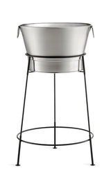 A large, round, TableCraft Products stainless steel tub sits on a black, tall, tripod-style metal stand with thin legs and a circular support. The tub has side handles and is perfect as a beverage tub set for holding ice drinks. Background is white.