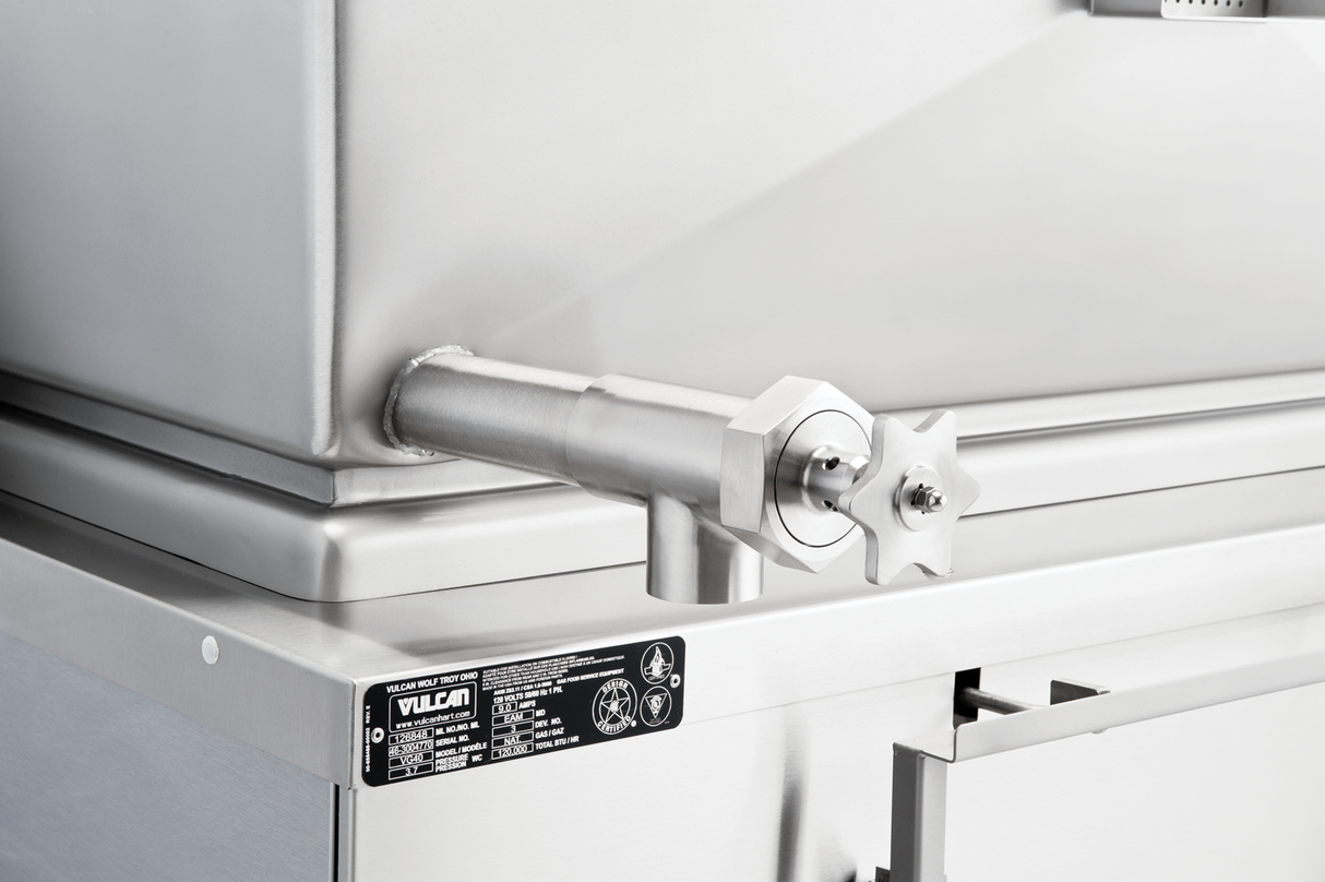 Close-up of a stainless steel commercial kitchen appliance, featuring a thick pipe with a star-shaped valve handle. This gas braising pan has a reflective surface and boasts a 40-gallon capacity, with an information label at the lower left corner.