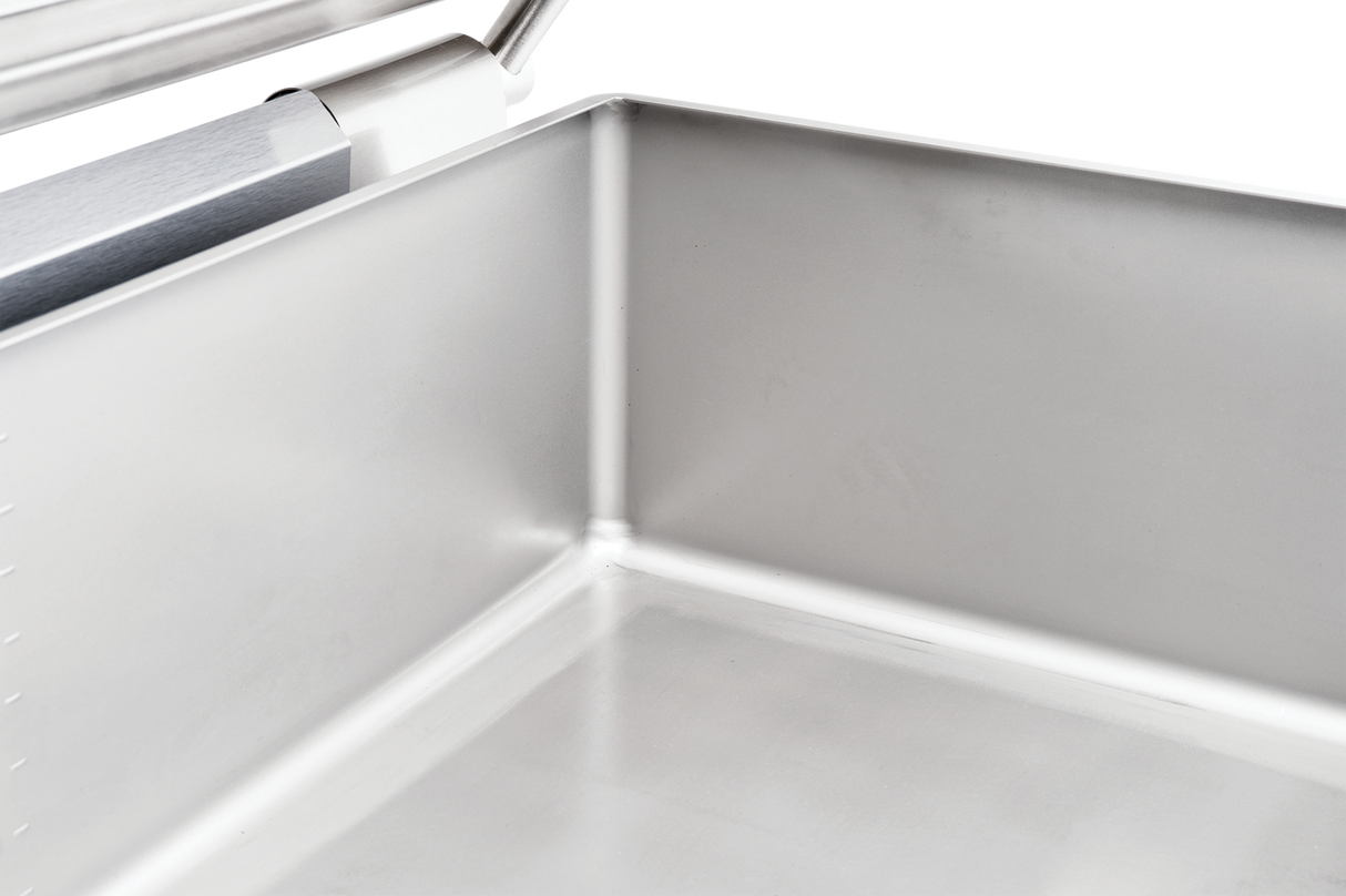 Close-up of the inside corner of a shiny, stainless steel tilting braising pan, showing smooth, reflective metal surfaces and welded seams. The top left features a metal handle. Perfect for multifunction cooking units with a 40 gallon capacity.