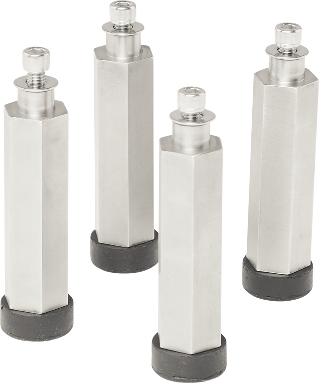 Four tall, hexagonal metal standoffs with black circular rubber bases stand upright, spaced apart like sturdy Berkel leg extensions. Each has a threaded screw on top and casts subtle shadows. The background is transparent.