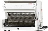 A commercial Bread Slicer with a white metal body, multiple parallel stainless steel blades for 3/4 slice thickness, a front-loading tray, and a side lever. The slicer is open on the countertop, showing its blade assembly and safety warnings.