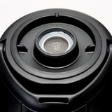 Close-up of a black plastic lid with a circular metallic mesh filter at the center, designed for an insulated beverage dispenser. The lid features concentric ridges, a matte finish, and smooth, rounded edges to aid heat retention.