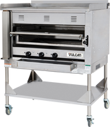 A large commercial stainless steel oven with three control knobs, vented front, and a pull-down door features the Vulcan logo. This Heavy Duty Chophouse Broiler sits on a metal stand with a lower shelf and four caster wheels for mobility.