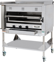 A large commercial stainless steel oven with three control knobs, vented front, and a pull-down door features the Vulcan logo. This Heavy Duty Chophouse Broiler sits on a metal stand with a lower shelf and four caster wheels for mobility.