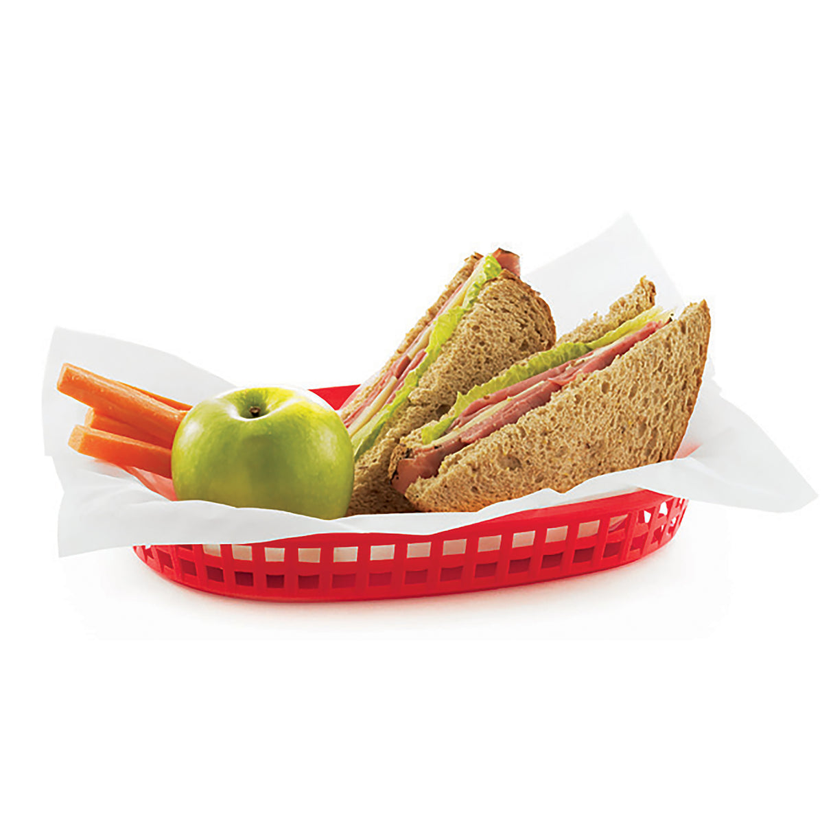 A red plastic display basket lined with white paper holds a sandwich cut in half, an unpeeled green apple, and several carrot sticks. The whole wheat sandwich has meat, cheese, lettuce, and tomato. The background is white.