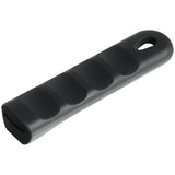 A Chef Approved black, rectangular pan handle sleeve made of textured silicone with four ergonomic finger grooves and a rounded end featuring a small oval hole, ideal for hanging or attaching a lanyard. The matte surface ensures a comfortable grip.
