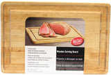 A rectangular TableCraft carving board with a groove along the edge is shown. The label displays sliced roast beef and includes product info in English, French, and Spanish. Label reads: Wooden Carving Board, 16 x 24 x 1.25.