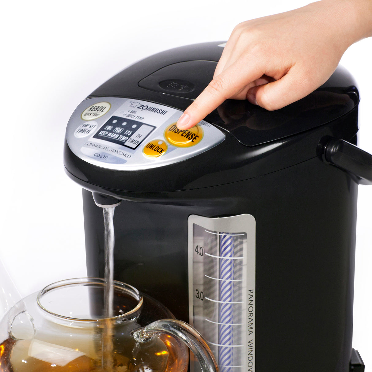 A hand presses the orange “Dispense” button on a black Zojirushi Water Boiler & Warmer, pouring hot water into a glass teapot below. The 5 liters water level gauge and digital control panel with labeled buttons are visible.