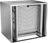 A stainless steel commercial ice machine with the outer side panel removed, revealing a white internal panel with grooves and channels for water flow or cooling, along with visible internal tubing and mechanical components on the side.