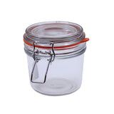 A clear TableCraft Products glass jar with lid features a round shape, metal clasp closure, and an orange rubber gasket. The airtight seal makes it ideal for food storage or as part of a stylish condiment jar set.