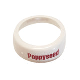 A white plastic Dispenser ID Collar with the word Poppyseed printed in bold red letters on its outer surface. The ring, from TableCraft, has a slightly rounded and smooth appearance and is photographed against a plain white background.