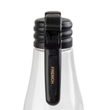 A close-up of a clear glass bottle with a black polypropylene flip-top lid. The lid features a lever labeled “FRENCH” in gold letters. The background is plain white, highlighting the dishwasher safe bottle and its distinctive closure mechanism.