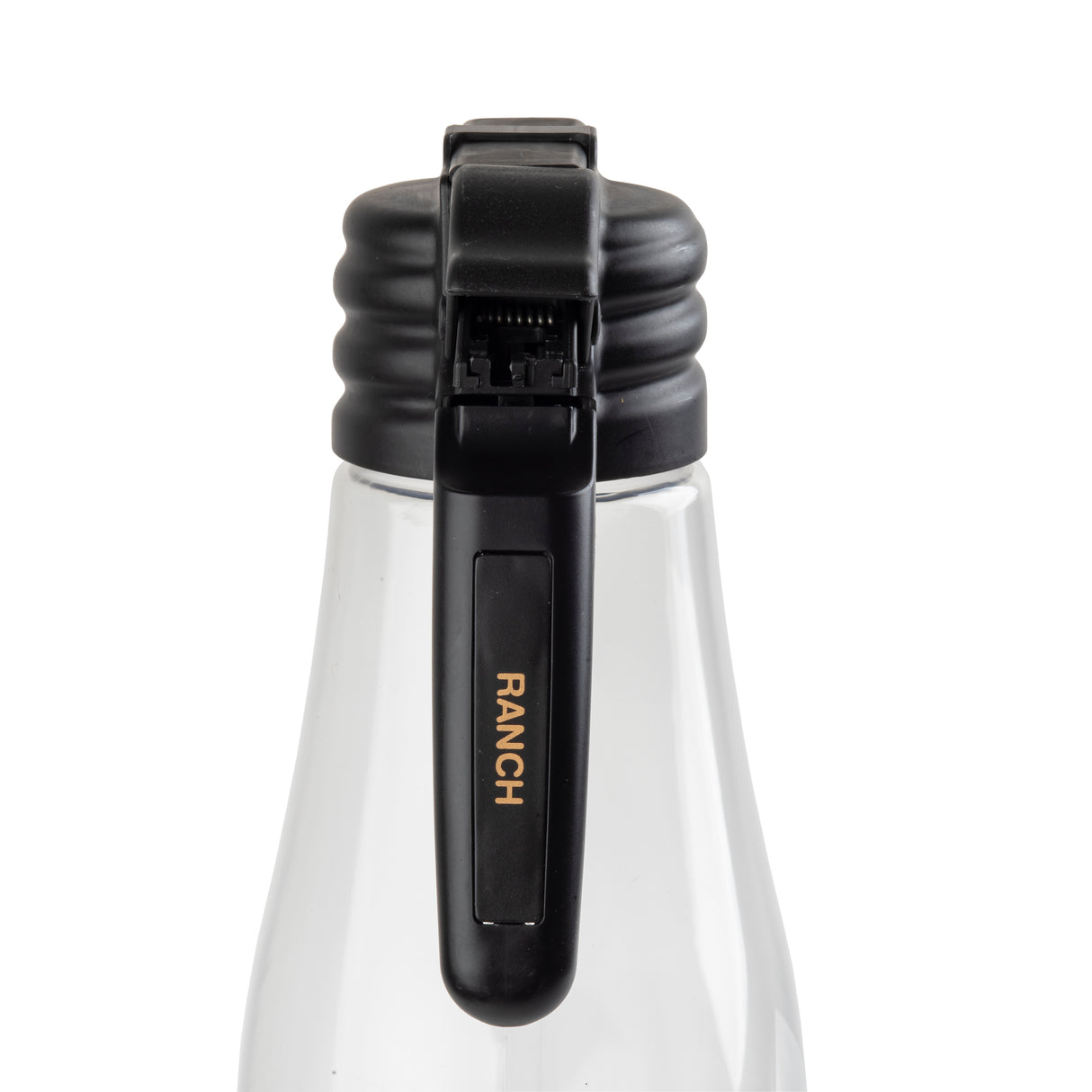 A clear bottle with a black polypropylene flip-top lid is shown close-up. The lid has a ribbed design and a black lever with RANCH written in gold letters like a Ranch name tag. The background is white, keeping the focus on the bottle and lid.