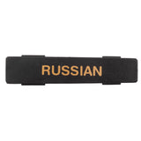 A rectangular black name tag badge with the word RUSSIAN in gold capital letters is centered on it. Clips or fasteners on the back suggest it’s meant to be worn on clothing. The background is plain white, and the badge appears to be dishwasher safe.