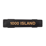 A rectangular black plastic Name Tag label with the words 1000 ISLAND printed in bold, gold-colored capital letters across the center. The flat, slightly glossy label is dishwasher safe and set against a plain white background.