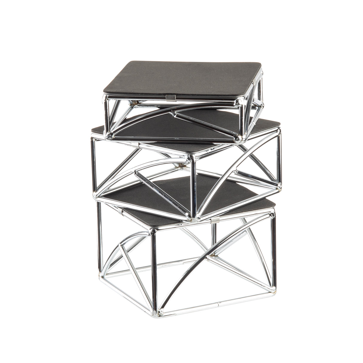Three square tables of varying sizes are stacked in a chic riser set. Each table features a black flat top and a chrome plated silver metal frame with intersecting lines, creating a modern, architectural appearance. The tables decrease in size from bottom to top.