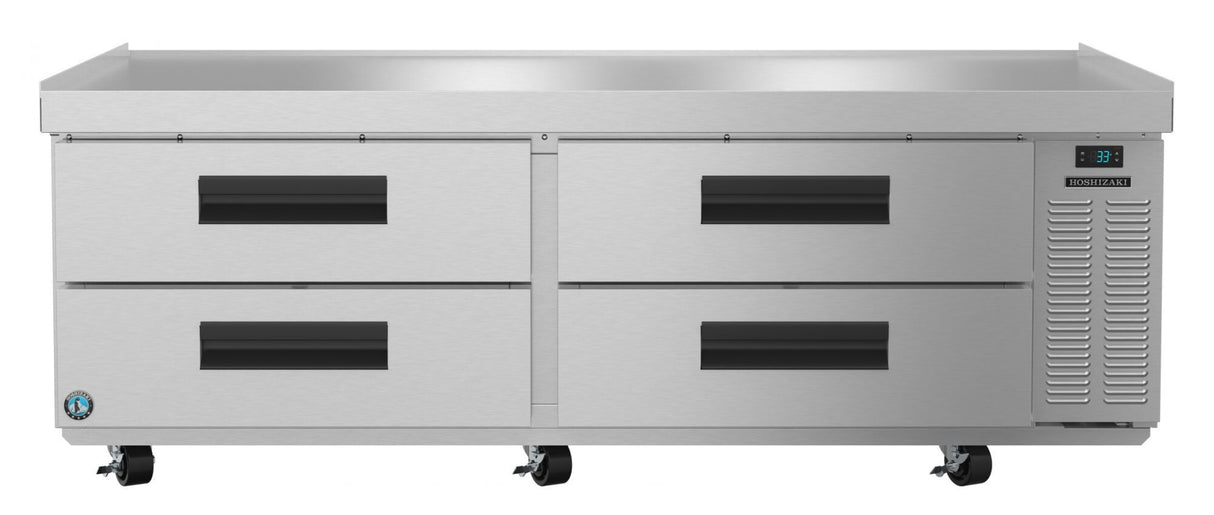 A large stainless steel refrigerator, designed as a low-profile refrigerated equipment stand, features four pull-out drawers, black handles, a digital temperature display on the right, ventilation panel, two front wheels, and a flat top surface against a white background.