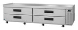 A large, stainless steel refrigerated stand with four black-handled pull-out drawers, ventilation grates on the right, a digital temperature display, and wheels for mobility. The flat top serves as a practical, modern low-profile equipment stand.