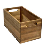 A rectangular Acacia Wood Crate with smooth slats, open top, and cutout handles on each short side. The natural finish highlights the grain patterns. This display crate is empty and positioned at an angle on a white background.