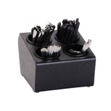 A black Flatware Organizer with 4 compartments holds metal spoons, forks, knives, and black plastic straws. The square container sits neatly on a countertop against a white background.