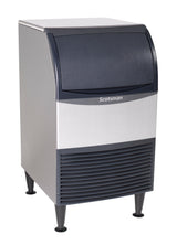 A stainless steel undercounter ice maker with bin, featuring a dark top lid, front vent, and four black legs. Its modern rectangular design and visible Scotsman brand name stand out against the white background.