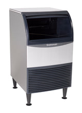 A freestanding silver and black undercounter ice maker with a bin, featuring a front louvered vent, black legs, and a dark translucent lid for easy access. The machine offers a modern, industrial design for efficient ice production.