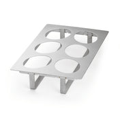 A full size stainless steel rack with six large circular cutouts and four supporting legs, designed to hold items such as jars or cups upright. The smooth, reflective cold food template is rectangular and elevated from the surface.