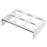 A white, rectangular TableCraft rack made of nylon coated cast aluminum features six large circular cutouts in two rows of three. The short vertical sides elevate it above the ground, making it ideal as a dressing template or for holding round containers.