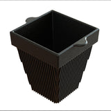 A black, square plant pot with flared sides and vertical ridges, reminiscent of a cast aluminum condiment bowl, features small handles on two opposite edges near the top rim. The pot has a modern, textured appearance and is set against a white background.