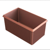 A rectangular, brown baking loaf pan with a copper finish features slightly flared edges and vertical ridges along the sides. The non-stick, shiny surface is empty, viewed from an angle showing the interior and side texture.