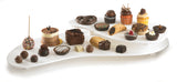 A white, three-tiered cast aluminum display holds assorted desserts, including cupcakes, truffles, chocolate cakes, cookies, and tarts. The sweets vary in shape and decoration and stay fresh on this dishwasher safe cold holding palette.