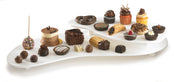 A white, two-tiered Duracoat coated cast aluminum display holds assorted desserts: cupcakes, chocolates, cake pops, cookies, brownies, tarts, pastries, and truffles in neat rows. Ideal for NSF cold holding palette setups. Many treats are topped with chocolate or icing.