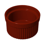 A small, round, deep-red souffle bowl with ribbed sides and a smooth rim. The ramekin is empty and sits on a white background at a slight angle above, highlighting its glossy surface, sturdy design, and dishwasher safe convenience.