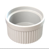 A white ceramic souffle bowl with a smooth interior and ribbed exterior sits on a white background. The round, empty ramekin is shown from a slightly elevated angle, ideal for cold holding desserts or appetizers.