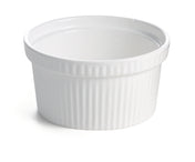 A white ceramic souffle bowl with a smooth interior and vertically ribbed exterior sits on a white surface. This small, round dish has a slightly flared rim and is ideal for baking or serving individual portions of food.