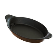 A black oval cast aluminum server with a brown outer surface, two textured handles for gripping, and a smooth, nonstick interior. The dish appears empty and is shown on a white background. It is also dishwasher safe.