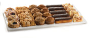 An extra large platter holds an assortment of pastries—fruit danishes, cinnamon rolls, crumb-topped muffins, chocolate eclairs, and cheese danishes—arranged neatly in rows on a white background.