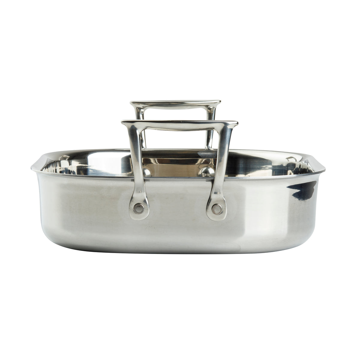 A shiny tri-ply stainless steel roasting pan is shown from the front. It has two sturdy rectangular handles and a wide, shallow design with a flat bottom, ideal for roasting. The pan is induction oven safe. The background is plain white.
