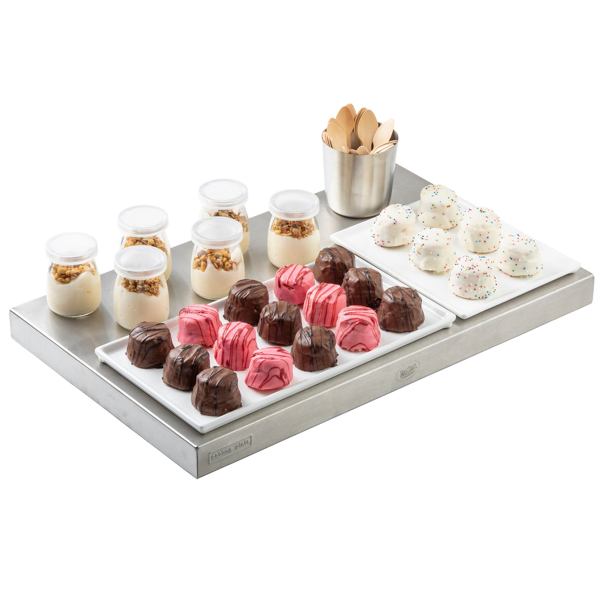 A black finish cast aluminum platter holds mini jars of yogurt with granola, a metal cup of wooden spoons, pink and brown marbled chocolates, and sprinkle-topped white dome desserts, all neatly arranged on rectangular white plates.