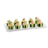 A white cast aluminum platter holds ten cucumber slices filled with a swirl of creamy pink topping, garnished with fresh dill sprigs. The cucumber pieces are neatly arranged in rows, keeping cold holding in mind against a plain white background.