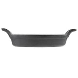 A black cast iron Mini Au Gratin Server viewed from the side, featuring two upward-curving handles on opposite sides. The pan has a rough, textured surface and slightly flared edges, set against a plain white background.