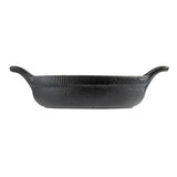 A black cast iron baking dish by TableCraft with a rough, textured surface. The oval-shaped mini server is shown from the side, featuring two wide, upward-curving handles at each end against a plain white background.